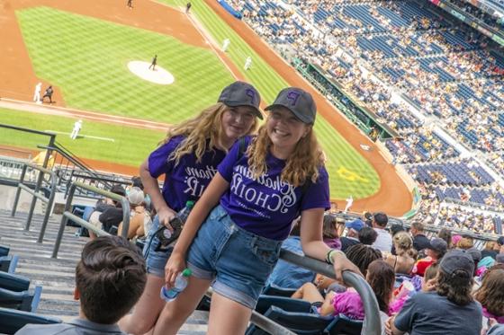  两名冰球突破app唱诗班的女学生穿着相配的紫色t恤，在匹兹堡海盗队的比赛中合影.